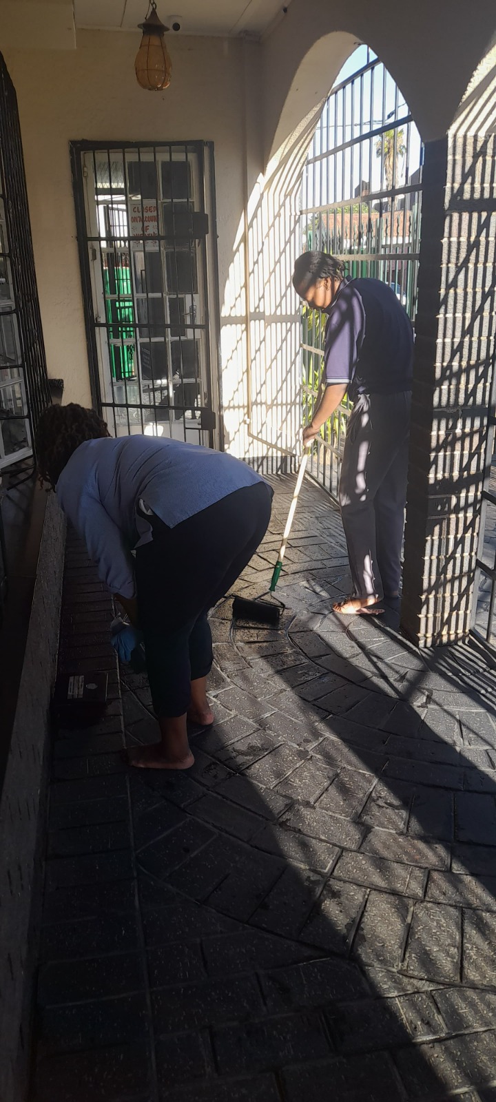 Team scrubbing and mopping a tiled outdoor passage